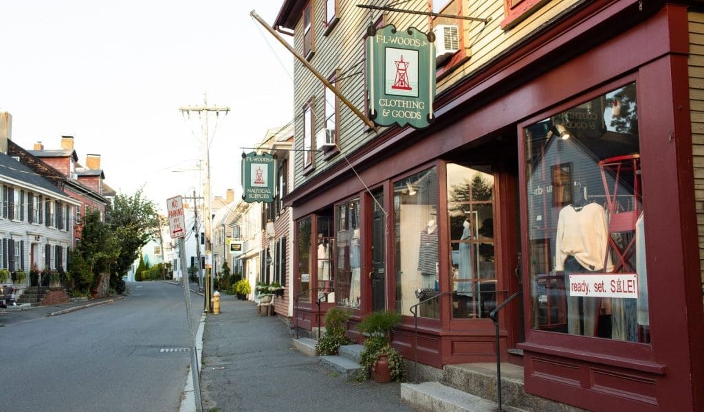 A photo of a block of dark red boutique storefronts in Marblehead MA on a clear day