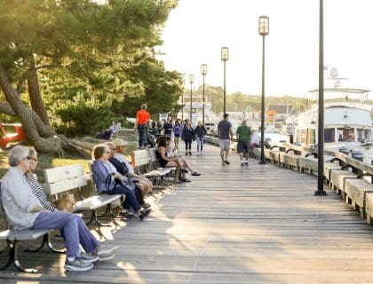 People Sitting on Benchs. and walking along the sidewalk overlooking the Merrimack river