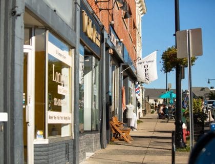 View of lively Humphrey Street in Swampscott MA filled with shops on a clear blue sky summer day