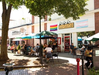 View of patrons eating under umbrellas at the outdoor tables in front of the Gulu-Gulu Cafe on a sunny day