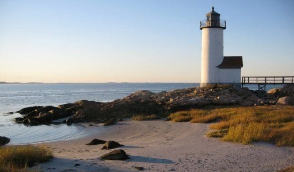 Landscape view of the Annisquam Lighthouse by the beach on a clear day at sunset.