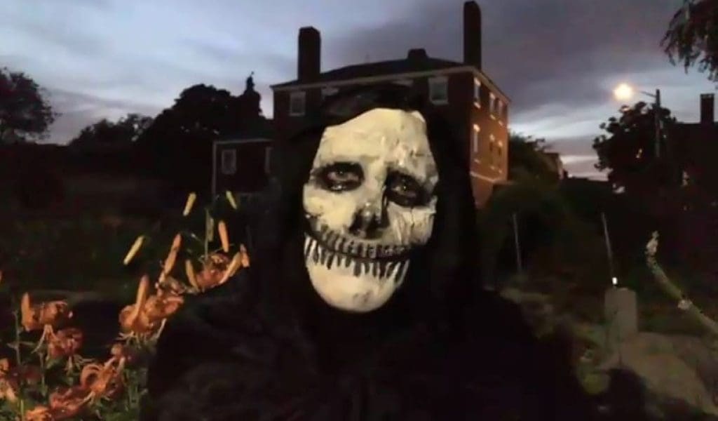 A person posing at night wearing a skeleton mask
