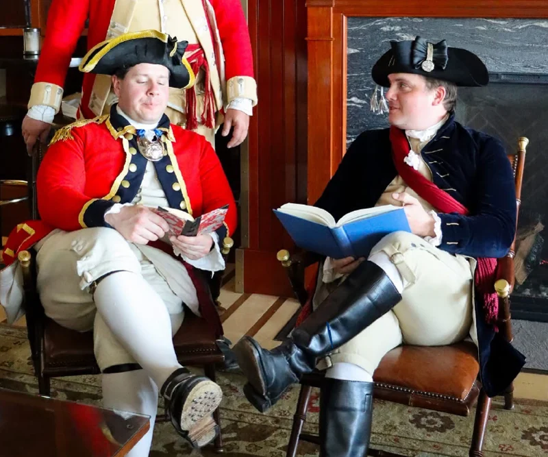Men dressed in colonial attire while reading books